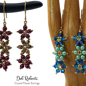 May include: A pair of gold crystal flower earrings with three tiers of flowers. The top and bottom tiers are made of burgundy beads and the middle tier is made of gold beads. The earrings are hanging from gold hooks.