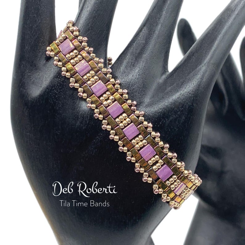 May include: A beaded bracelet with a geometric pattern in shades of purple and gold. The bracelet is made with small, square beads and has a delicate, intricate design. The text "Deb Roberti Tila Time Bands" is visible below the bracelet.