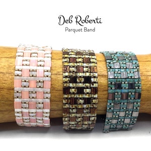 May include: Three beaded bracelets in a parquet pattern. The bracelets are pink and white, brown and white, and teal and silver.