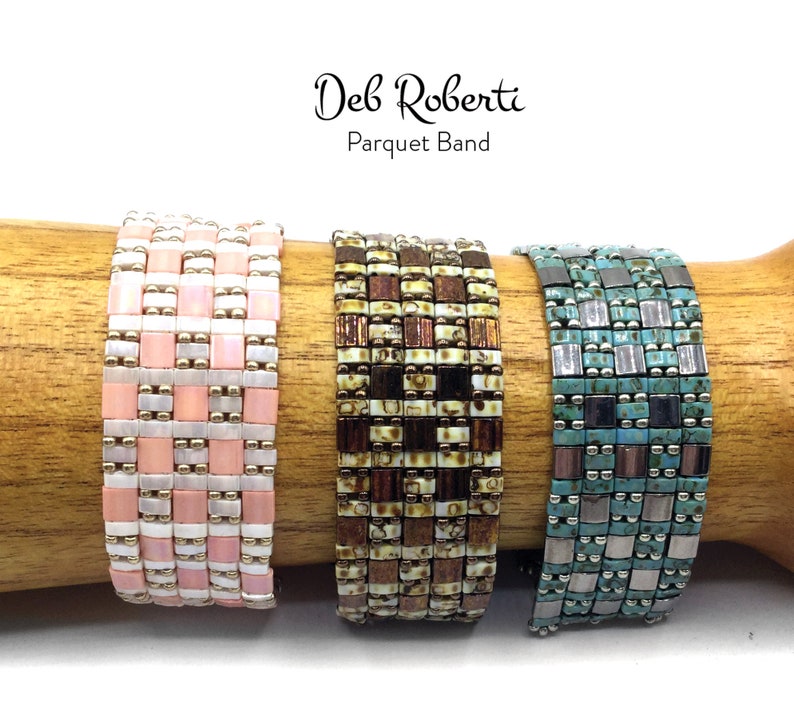 May include: Three beaded bracelets in a parquet pattern. The bracelets are pink and white, brown and white, and teal and silver.
