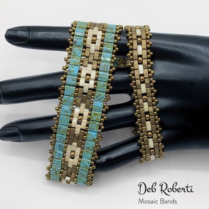 Op de afbeelding: Twee kralenarmbanden met een mozaïekpatroon. De armbanden zijn gemaakt van turquoise, gouden en witte kralen. De armbanden bevinden zich op een zwarte mannequinhand. De tekst "Deb Roberti Mosaic Bands" staat onderaan de afbeelding.