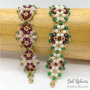 Può includere: Due braccialetti di perline con un design floreale. Un braccialetto presenta perline rosse, verdi e rosa chiaro, mentre l'altro ha perline bianche, rosse e verdi. I braccialetti sono adornati con dettagli color oro e un piccolo ciondolo dorato alla fine. Il testo "Deb Roberti Rosebud Bracelet" è visibile.