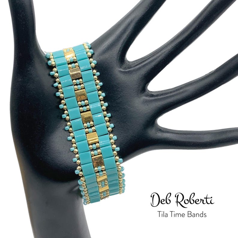 May include: A turquoise and gold beaded bracelet on a black hand model. The bracelet is made with small square beads and has a geometric pattern. The text "Deb Roberti Tila Time Bands" is visible below the bracelet.