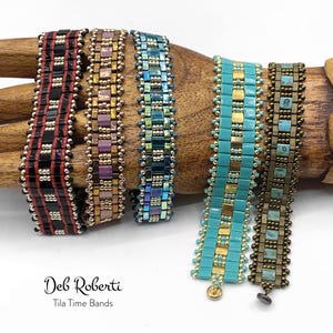 May include: Five beaded bracelets in various colors and patterns, including black, red, gold, purple, blue, turquoise, and brown. The bracelets are displayed on a wooden hand form. The text "Deb Roberti Tila Time Bands" is visible below the bracelets.