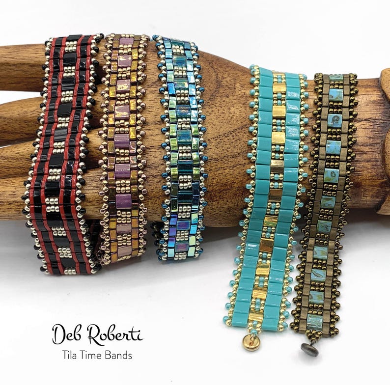 May include: Five beaded bracelets in various colors and patterns, including black, red, gold, purple, blue, turquoise, and brown. The bracelets are displayed on a wooden hand form. The text "Deb Roberti Tila Time Bands" is visible below the bracelets.