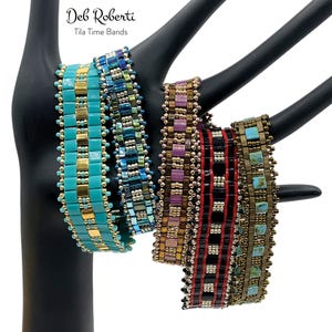 May include: Four beaded bracelets in various colors and patterns, including turquoise, purple, red, and brown. The bracelets are made with small, square beads and are displayed on a black mannequin hand. The text "Deb Roberti Tila Time Bands" is visible above the bracelets.