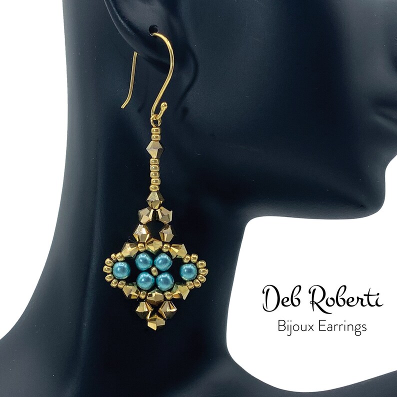 Może przedstawiać: Złote i turkusowe kolczyki z koralik&oacute;w o geometrycznym wzorze. Kolczyki wiszą na uchu manekina. Tekst "Deb Roberti Bijoux Earrings" jest widoczny w prawym dolnym rogu obrazu.