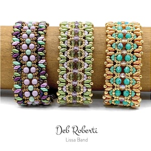 May include: Three beaded bracelets with a green, purple, and orange color scheme. The bracelets are made with small seed beads and feature a geometric pattern. The bracelets are displayed on a wooden surface. The text "Deb Roberti Lissa Band" is displayed below the bracelets.