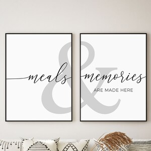May include: Two black framed prints with a gray ampersand symbol and the text "meals & memories are made here" in black cursive font.