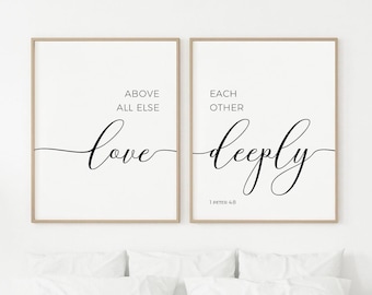 May include: Two rectangular wall art prints in light wood frames featuring black text on a white background. The left print reads ABOVE ALL ELSE love, and the right print reads EACH OTHER deeply 1 PETER 4:8 in a mix of sans-serif and script fonts.