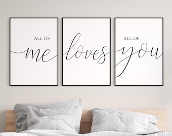 May include: Three framed art prints with the words "ALL OF ME LOVES YOU" in elegant black script. The prints are displayed above a bed with white bedding and gray pillows, creating a serene bedroom scene.