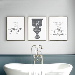 May include: A set of three rectangular wall art prints with white backgrounds and dark gray text. The left print reads Have a nice poop, the center print shows a toilet graphic with the text shit is about to go down, and the right print reads Wash your hands you filthy animal.