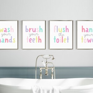 May include: Four framed bathroom art prints with colorful text: "wash your hands," "brush your teeth," "flush the toilet," and "hang your towel." The text is in a playful, rounded font, with each word in a different pastel color.