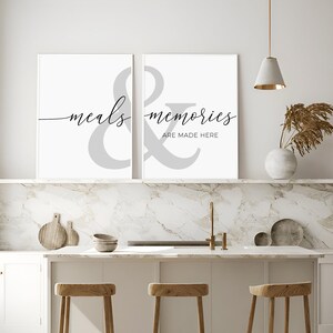May include: Two white framed prints with the text "meals & memories are made here" in black script. The ampersand is a large gray symbol.