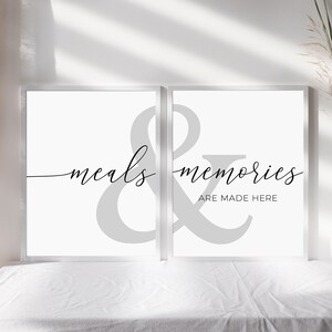 May include: Two white framed prints with a gray ampersand symbol in the center. The left print says "meals" and the right print says "memories are made here".