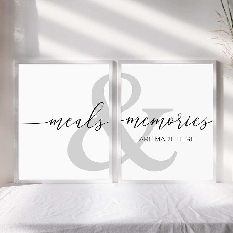 May include: Two white framed prints with a gray ampersand symbol in the center. The left print says "meals" and the right print says "memories are made here".