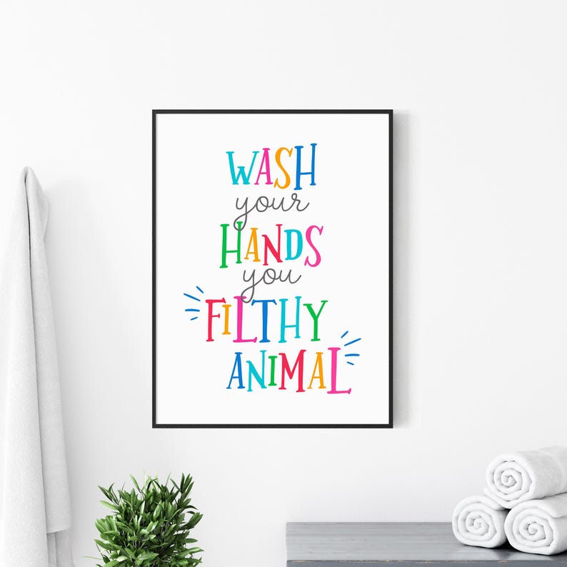 May include: A rectangular wall art print in a black frame featuring the multicolored text WASH your HANDS you FILTHY ANIMAL on a white background. The words are written in various bright colors including blue, orange, green, pink, and yellow.