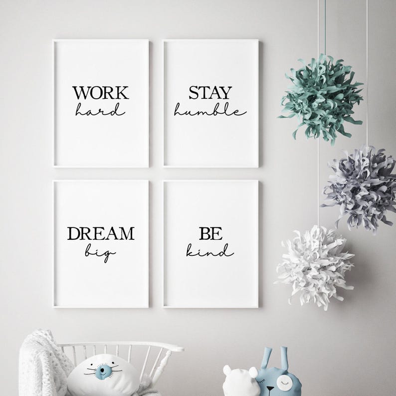 May include: Four framed white prints with black text that reads "WORK hard", "STAY humble", "DREAM big", and "BE kind". Decorative hanging paper pom-poms in shades of green, gray, and white are suspended from the ceiling.