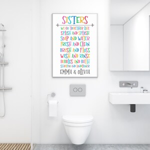 May include: A colorful bathroom sign with the text "SISTERS" and a list of activities, including "Splish and Splash", "Soap and Water", "Fresh and Clean", "Brush and Floss", "Wash and Rinse", "Bubbles and Bath", "Shampoo and Conditioner", and "Emma & Olivia".