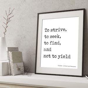 Puede incluir: Impresión tipográfica en blanco y negro con la cita "Esforzarse, buscar, encontrar y no ceder" atribuida a Alfred Lord Tennyson. La impresión está enmarcada en un marco negro y se muestra en un estante blanco con libros y un jarrón.
