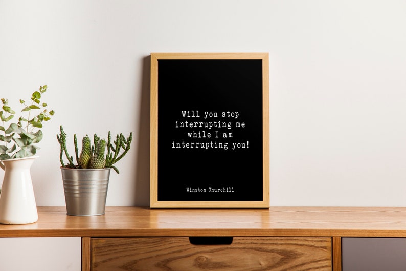 May include: A black framed print with a white background and a quote in white text that reads "Will you stop interrupting me while I am interrupting you!"  The quote is attributed to Winston Churchill.