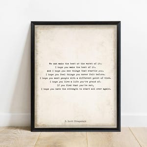 May include: A framed wall art print featuring a quote by F. Scott Fitzgerald in a typewriter-style font on a textured, off-white background. The text reads: We can make the best or the worst of it. I hope you make the best of it. And I hope you see things that startle you. I hope you feel things you never felt before. I hope you meet people with a different point of view. I hope you live a life you're proud of. If you find that you're not, I hope you have the strength to start all over again.