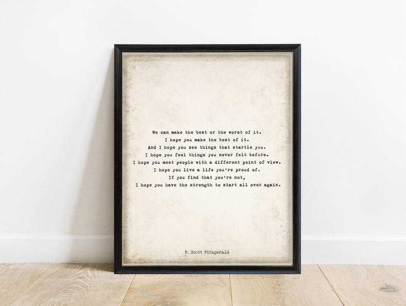 May include: A framed wall art print featuring a quote by F. Scott Fitzgerald in a typewriter-style font on a textured, off-white background. The text reads: We can make the best or the worst of it. I hope you make the best of it. And I hope you see things that startle you. I hope you feel things you never felt before. I hope you meet people with a different point of view. I hope you live a life you're proud of. If you find that you're not, I hope you have the strength to start all over again.