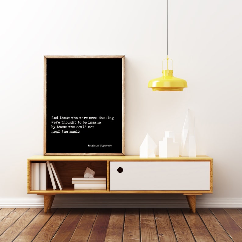 May include: A black and white framed print with a quote by Friedrich Nietzsche: "And those who were seen dancing were thought to be insane by those who could not hear the music."