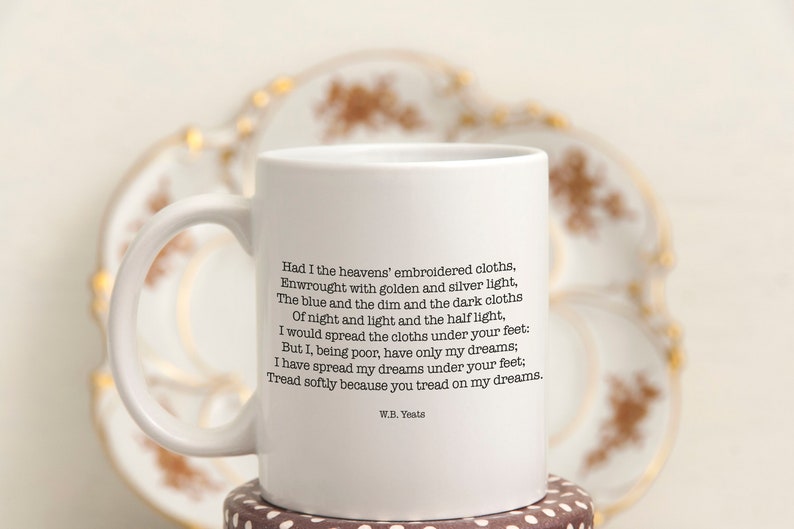 May include: White ceramic mug with a black quote by W.B. Yeats: "Had I the heavens' embroidered cloths, Enwrought with golden and silver light, The blue and the dim and the dark cloths Of night and light and the half light, I would spread the cloths under your feet: But I, being poor, have only my dreams; I have spread my dreams under your feet: Tread softly because you tread on my dreams."