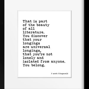 May include: A framed wall art print featuring black typewriter-style text on a white background. The quote reads: That is part of the beauty of all literature. You discover that your longings are universal longings, that you're not lonely and isolated from anyone. You belong. Signed f scott fitzgerald.