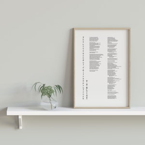 May include: A framed print of a poem titled "The Love Songs of J. Alfred Prufrock" by T.S. Eliot. The print is hanging on a white shelf with a small vase of greenery in front of it.