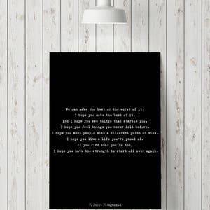 May include: A rectangular black wall art print featuring white typewriter-style text that reads: We can make the best or the worst of it. I hope you make the best of it. And I hope you see things that startle you. I hope you feel things you never felt before. I hope you meet people with a different point of view. I hope you live a life you're proud of. If you find that you're not, I hope you have the strength to start all over again. F. Scott Fitzgerald.