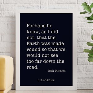 May include: Black and white typography quote on a white framed poster with the text "Perhaps he knew, as I did not, that the Earth was made round so that we would not see too far down the road. - Isak Dinesen Out of Africa"