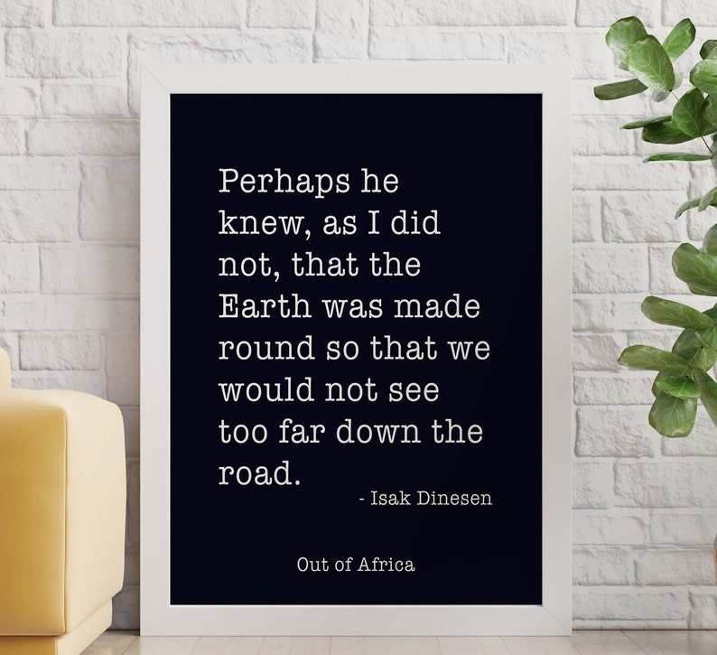 May include: Black and white typography quote on a white framed poster with the text "Perhaps he knew, as I did not, that the Earth was made round so that we would not see too far down the road. - Isak Dinesen Out of Africa"