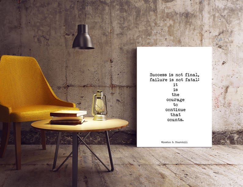 May include: A motivational quote by Winston S. Churchill printed on a white canvas mounted on a wall. The quote reads: "Success is not final, failure is not fatal: it is the courage to continue that counts."