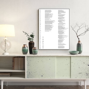 May include: A black and white framed print of a poem by T.S. Eliot, "The Love Song of J. Alfred Prufrock", hanging on a white wall above a light green cabinet with two doors. The cabinet has a shelf and is decorated with black speckles. There are two vases with green and brown flowers on the cabinet.