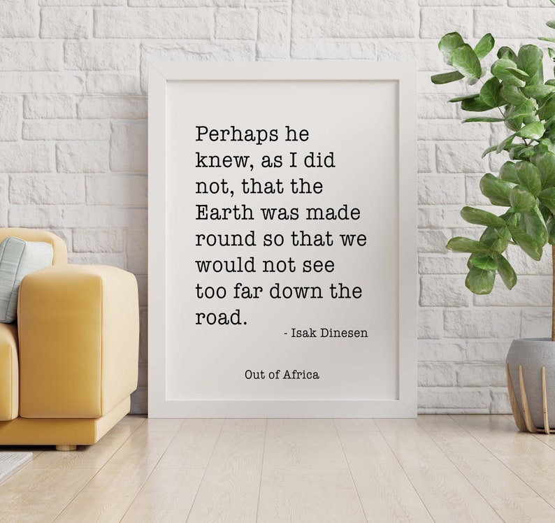 May include: A black and white framed print with a quote by Isak Dinesen from "Out of Africa" that reads: "Perhaps he knew, as I did not, that the Earth was made round so that we would not see too far down the road."