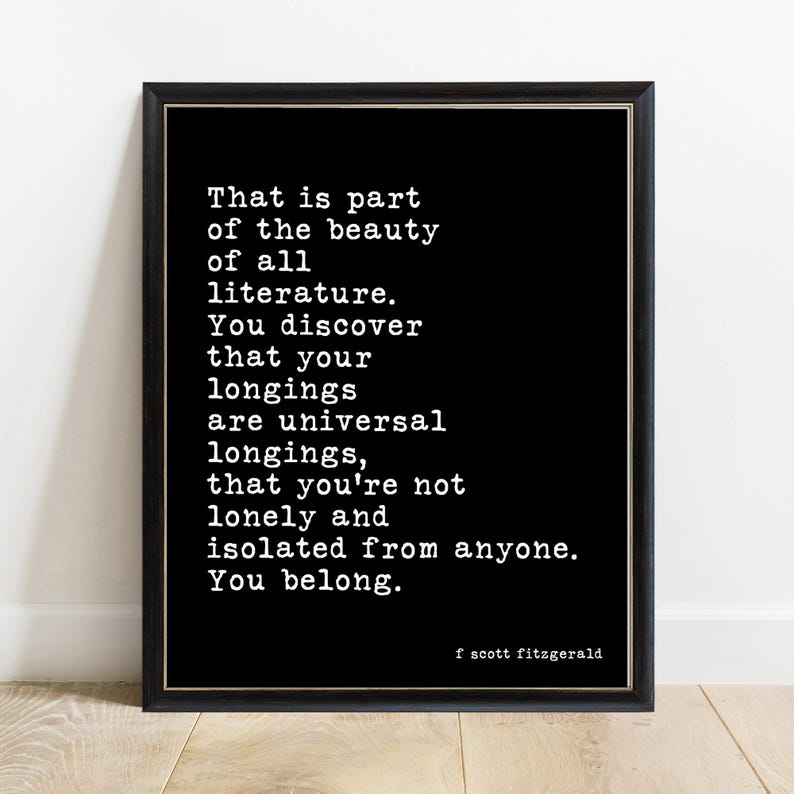 May include: A black framed wall art print featuring white typewriter-style text that reads: That is part of the beauty of all literature. You discover that your longings are universal longings, that you're not lonely and isolated from anyone. You belong. f scott fitzgerald.