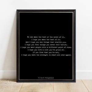 May include: A black framed wall art print featuring white typewriter-style text that reads: We can make the best or the worst of it. I hope you make the best of it. And I hope you see things that startle you. I hope you feel things you never felt before. I hope you meet people with a different point of view. I hope you live a life you're proud of. If you find that you're not, I hope you have the strength to start all over again. F. Scott Fitzgerald.