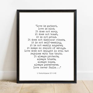 May include: A framed wall art print featuring black typewriter-style text on a white background. The text reads: Love is patient, love is kind. It does not envy, it does not boast, it is not proud. It does not dishonor others, it is not self-seeking, it is not easily angered, it keeps no record of wrongs. Love does not delight in evil but rejoices with the truth. It always protects, always trusts, always hopes, always perseveres. Love never fails... 1 Corinthians 13 : 4-8.