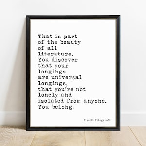 May include: A framed wall art print featuring black typewriter-style text on a white background. The quote reads: That is part of the beauty of all literature. You discover that your longings are universal longings, that you're not lonely and isolated from anyone. You belong. Signed f scott fitzgerald.