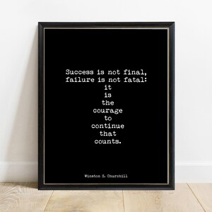 May include: A black framed wall art print featuring white typewriter-style text that reads: Success is not final, failure is not fatal: it is the courage to continue that counts. Winston S. Churchill. The frame is thin, dark, and rectangular.