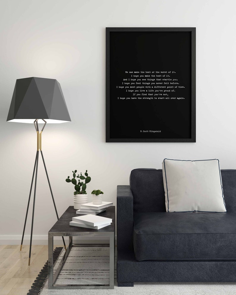 May include: A black framed wall art print featuring white typewriter-style text of a quote by F. Scott Fitzgerald. The text reads: We can make the best or the worst of it. I hope you make the best of it. And I hope you see things that startle you.
