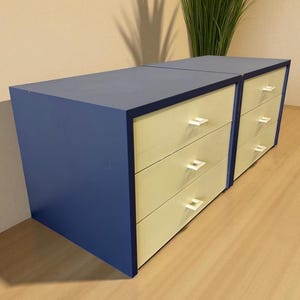 Op de afbeelding: Twee bijpassende blauwe en crèmekleurige dressoirs met elk zes lades. De dressoirs hebben een modern design met witte handgrepen. De dressoirs staan naast elkaar.