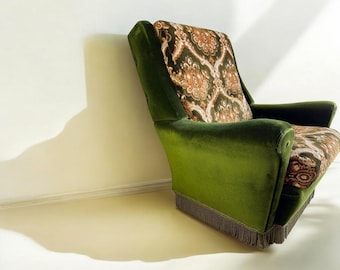 May include: A vintage armchair with a green velvet exterior and a patterned back and seat. The pattern features shades of brown and orange. The chair has a fringed trim along the bottom edge.
