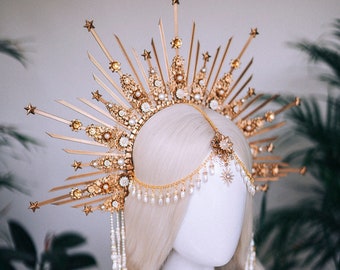 Peut inclure: Une couronne dorée avec un motif en étoile et des accents de perles. La couronne est portée sur une tête de mannequin blanche.