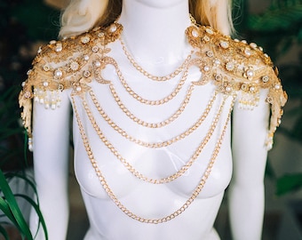 May include: Gold chain necklace with two gold and pearl shoulder pieces. The necklace has multiple layers of chain and the shoulder pieces have a floral design.