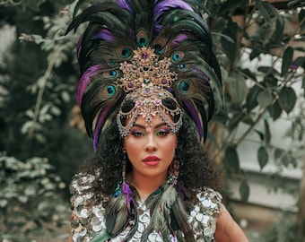 Peut inclure: Une femme portant une robe en sequins argentés avec un grand couvre-chef en plumes noires et violettes et des accents dorés.