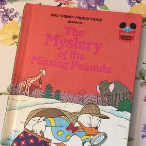 May include: A vintage children's book cover featuring Donald Duck as a detective, searching for missing peanuts. The cover is red with the title "The Mystery of the Missing Peanuts" in pink and white lettering. The book is part of Disney's Wonderful World of Reading.