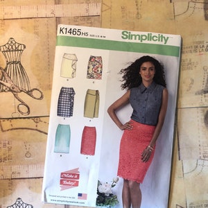 Puede incluir: Un patrón de costura para una falda, Simplicity patrón número K1465 H5, talla ES 38-46. El patrón incluye cinco estilos de faldas diferentes, incluyendo una falda con volantes, una falda de estampado floral, una falda envolvente, una falda a cuadros y una falda lisa. El patrón también incluye una foto de una mujer usando una falda de encaje coral.